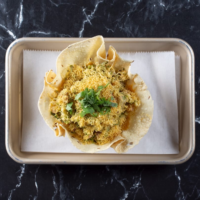 Tulsi Kitchen's Indian dish, a papadum bowl filled with savory mixture, topped with sev and cilantro.