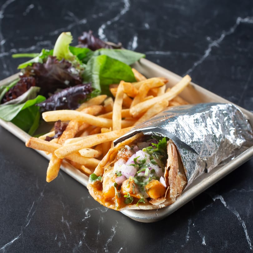 Tulsi Kitchen's Indian wrap with fries and a side salad on a metal tray.